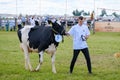 Young man leading cow in paddock