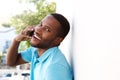 Young man leaning to wall outside and talking on cell phone Royalty Free Stock Photo