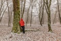 Young man is leaning on a tree in a winter forest Royalty Free Stock Photo