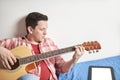 Young man learning to play guitar at home using his tablet Royalty Free Stock Photo