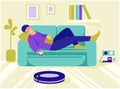 A young man lies on the couch, controls the robot vacuum cleaner from the remote control. Modern wireless equipment for