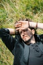 Young man lies on the green grass covering his face with his hand from the sun Royalty Free Stock Photo