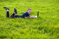 Young man lies on green grass with laptop and working Royalty Free Stock Photo