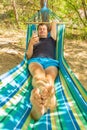 A young man lies on a hammock and looks at a smartphone on a summer sunny day