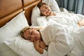 Young man lies next to a dozing blonde