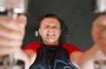 A young man lies on a sports bench lifting dumbbells with a tense face in the gym during a workout