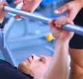 Young man lifting the barbell in gym with instructor Royalty Free Stock Photo