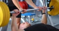 Young man lifting the barbell in gym with instructor Royalty Free Stock Photo