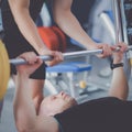 Young man lifting the barbell in gym with instructor Royalty Free Stock Photo