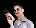 Lurking insanity. Young man lifting a mask off his face and revealing a deranged expression.