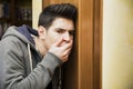 Young man listening in behind a door