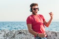 Young man listening to the music on headphones playing imaginary guitar