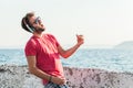 Young man listening to the music on headphones playing imaginary guitar