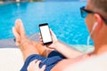 Man listening to music and holding mobile phone in hand by the pool. Royalty Free Stock Photo