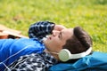 Young man listening to music while lying on green grass in park Royalty Free Stock Photo