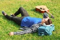 Young man listening to music while lying on green grass in park Royalty Free Stock Photo