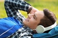 Young man listening to music while lying on green grass in park Royalty Free Stock Photo