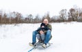 Young man with the little boy sitting on sledge in snow Royalty Free Stock Photo