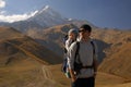 Young man with little child in baby carrier backpack near snowy mountain glacier at autumn, travelling with kids