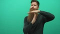 Young man with long beard standing makes timeout gesture with hands in green studio setting; caution Royalty Free Stock Photo