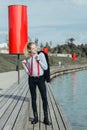 Young man with long blond hair in a suit in a red tie and suspenders calmly posing, throwing a black jacket Royalty Free Stock Photo