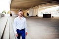 Young man in long white shirt and blue pants walking looking at camera, with short beard and earring Royalty Free Stock Photo