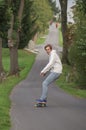 Young man on a longboard driving down an empty road Royalty Free Stock Photo