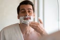 Young man look in mirror shaving in bathroom Royalty Free Stock Photo