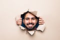 Young handsome man looking through beige paper hole Royalty Free Stock Photo