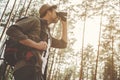 Young man is looking through binocular at forest