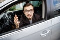 Young man is looking at the camera while sitting at his car. He is explaining something Royalty Free Stock Photo