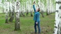 A young man is looking for a cellular network in a birch forest. A man is talking on the phone, but the connection is Royalty Free Stock Photo