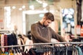 A young man looking through the clothes on a rail, a scene at a Royalty Free Stock Photo