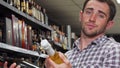 Young man looking confused while choosing wine