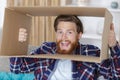 young man looking excitedly through cardboard box Royalty Free Stock Photo