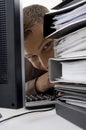 Young man looking between the files and computer Royalty Free Stock Photo