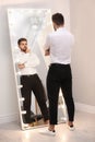 Young man looking at himself in smart mirror