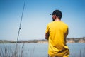 Young man looking on horizont seascape and holds a fishing rod and catches fish in the nature background, hipster fisherman spends Royalty Free Stock Photo