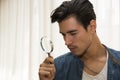 Young man looking through a magnifying glass Royalty Free Stock Photo