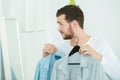 young man looking in mirror comparing shirts Royalty Free Stock Photo