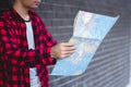 Young man looking in open map. Traveler standing with road map i