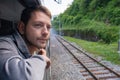 Young man looking out of train window while traveling by railway through Balkans. Male traveler looking out sleeping car Royalty Free Stock Photo