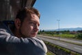 Young man looking out of train window while traveling by railway through Balkans. Male traveler looking out sleeping car Royalty Free Stock Photo