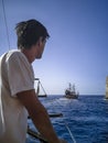 Young man looking at pirate schooner in the open ocean, vertical. A tourist admires the seascape from the deck of the ship, view