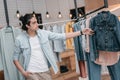 Young man looking at stylish clothes hanging on hangers in boutique Royalty Free Stock Photo