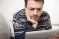 Young man looking at a tablet computer while lying on the couch. Royalty Free Stock Photo