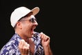 Young man looking to the side, laughing, celebrating, with black sunglasses, white cap and blue and white Hawaiian shirt Royalty Free Stock Photo