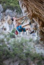 Young man looking up while climbing challenging route on cliff Royalty Free Stock Photo