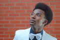 Young man looking up wearing bow tie white jacket brick wall Royalty Free Stock Photo