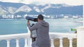 Young man looks through binoculars on observation deck. Media. Man looks through binoculars in rain in summer. View of Royalty Free Stock Photo